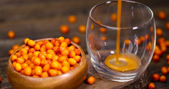a glass of natural orange juice and frozen sea buckthorn berries photo