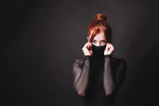 mysterious lady or woman with red hair and elegant black dress concealing part of her face with turtleneck mask photo