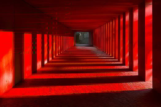 Red tunnel creating long shadows in modern architecture photo