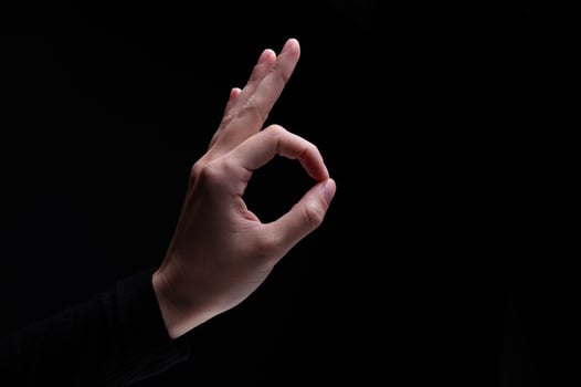 Female hand showing the ok gesture on a black background. Okey hand sign photo