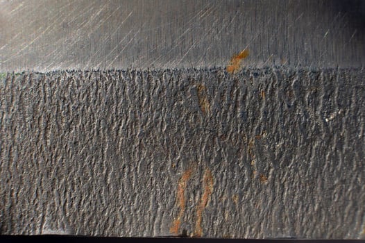 Close-up of the textured surface of a kitchen knife with rust stains. Macro shot of metal surfaces photo