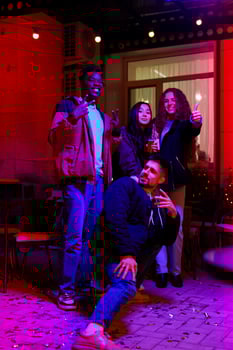 Group of friends celebrating with drinks and sparklers at a lively outdoor gathering in the evening photo