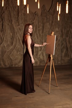 An artist poses gracefully by a blank canvas in a dramatic setting, evoking emotion photo