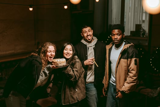 Friends celebrating with a cake during a cozy gathering in a well-lit indoor space at night photo
