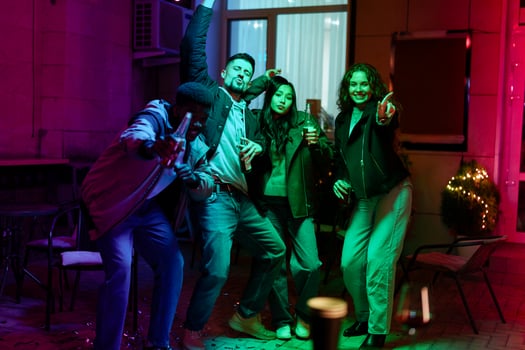 Friends celebrate joyfully at night with colorful lights in a cozy outdoor gathering photo