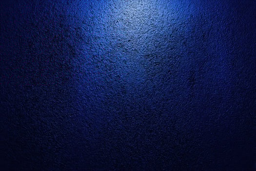 A dark blue wall with a light shining on it photo
