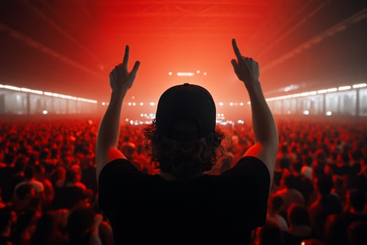 A man in a black shirt and hat is raising his hands in front of a crowd photo