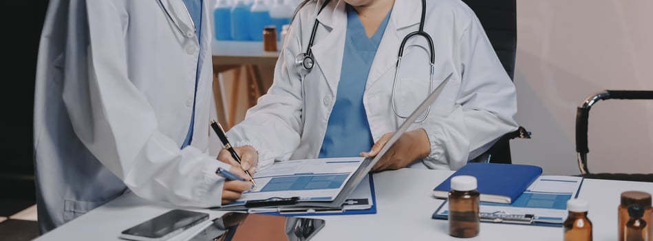 Two doctors are working on a document at a desk photo