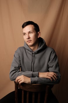 A Contemplative Young Man Dressed in a Casual Hoodie Sitting Comfortably on a Chair photo