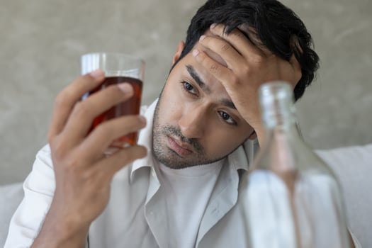 Depressed young man addict feeling bad drinking whiskey alone at home, stressed frustrated lonely drinking alcohol suffers from problematic liquor, alcoholism, life and family problems photo