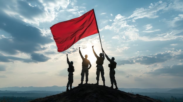 Silhouette of three people holding a red flag photo