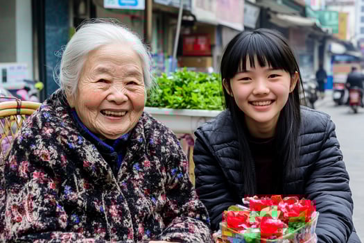 An asian woman and an older woman sitting on a sidewalk photo