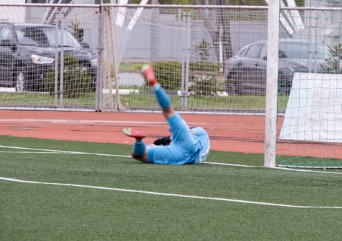 goalkeeper lying on football field after conceding goal, selective focus photo