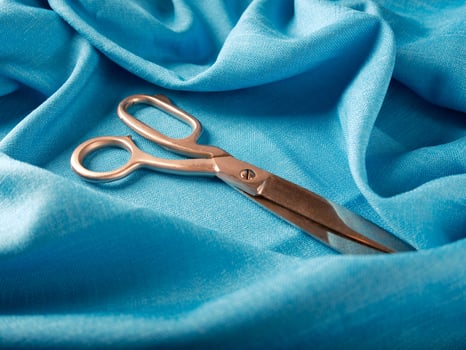 tailor's scissors lie on blue linen fabric photo