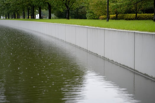 A man walking along a wall with water on the ground photo