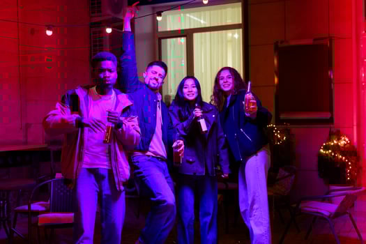 Group of friends celebrating at a vibrant evening gathering with drinks in hand photo