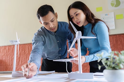 Innovative Wind Energy Solutions. Male and female engineers collaborating on wind turbine models. photo