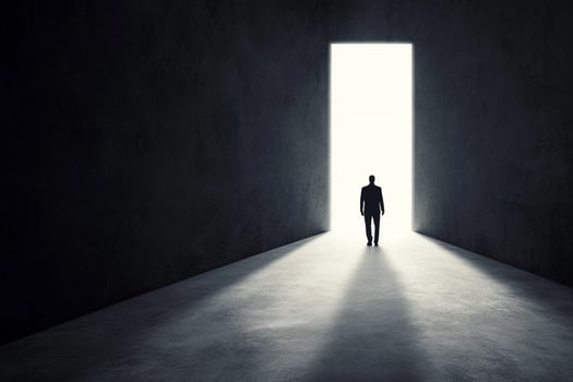 A man standing in an empty room with a light coming from the door photo