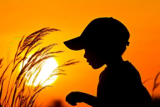 Silhouette of a child in a hat looking at the sun photo