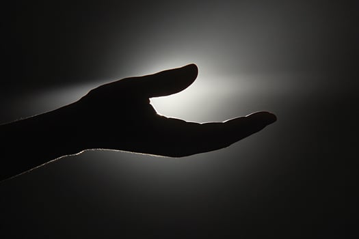 A person's hand is reaching out to the light photo