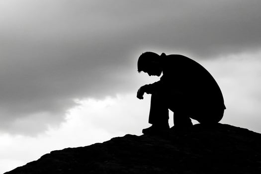 A man sitting on top of a mountain with a dark sky photo