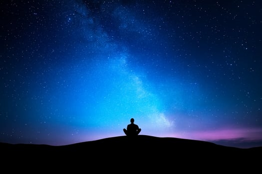Silhouette of man meditating under the stars at night photo