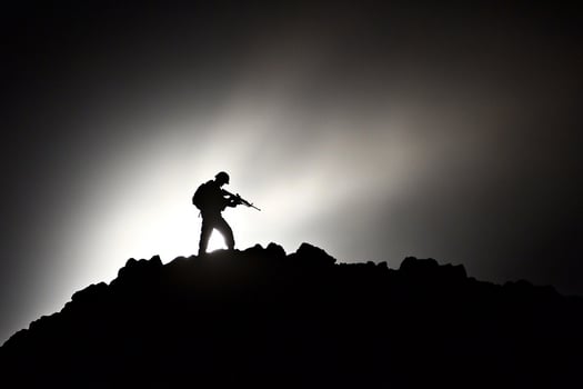 A silhouette of a man standing on top of a mountain photo