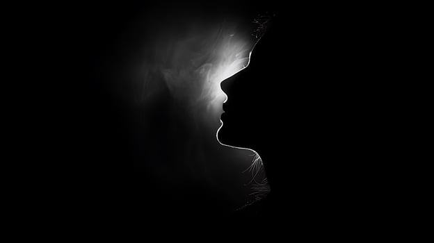 Silhouette of a woman's face in profile with a bright light behind her head in black and white photo