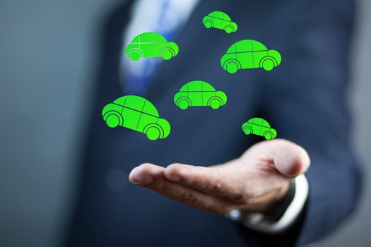 A man in a suit is holding a green car photo