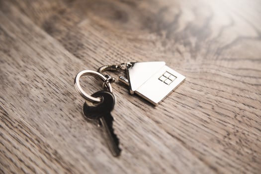 A house keychain and a key on a wooden table photo