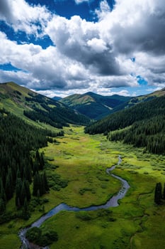 Vast green valley with river under cloudy sky in the mountains photo