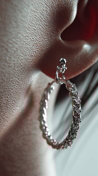 Close-up view of ornate silver hoop earring worn by individual with dark hair, showcasing intricate design and texture photo