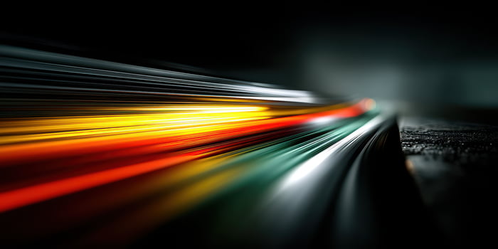 Dynamic light trails create a vibrant display on a dark road surface during nighttime photo