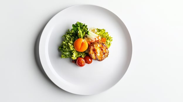 A white plate with a salad and chicken on it photo