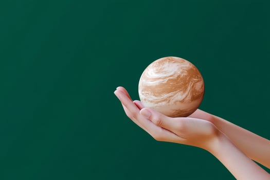 Holding a small planet model in hands against a green background with swirling patterns photo