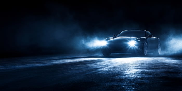 Sleek black sports car illuminated by headlights in a moody atmosphere at night photo