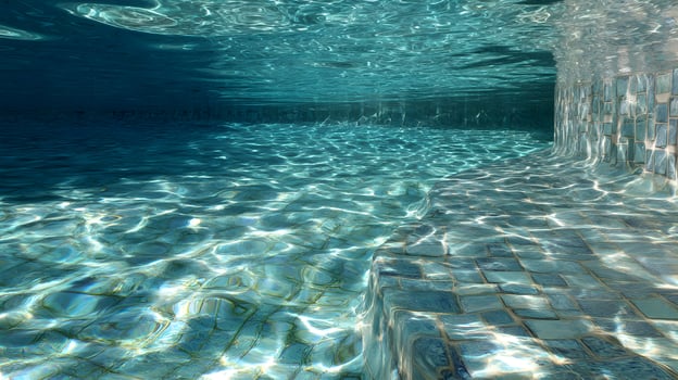 Underwater view of a swimming pool shows light filtering through the surface casting patterns below photo