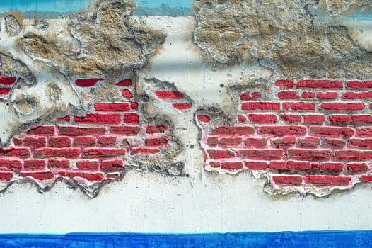 Weathered wall with peeling plaster revealing vibrant red bricks, accented by blue hues, creating a unique grunge texture and abstract background photo