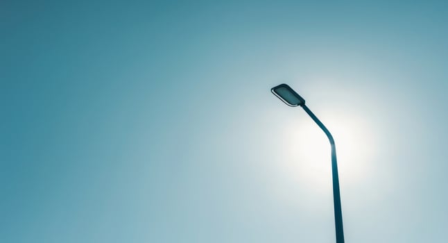 A street light is shown against a blue sky photo