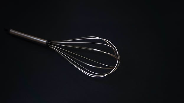 Stainless steel whisk on black background photo