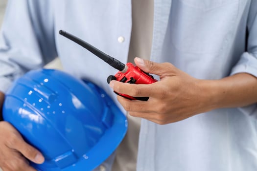 Safety and Communication in Construction. Close-up of engineer holding helmet and walkie-talkie. photo