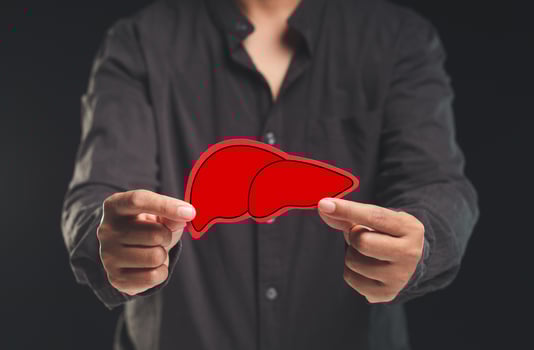 Man holding a symbol of a liver while standing against a black background photo