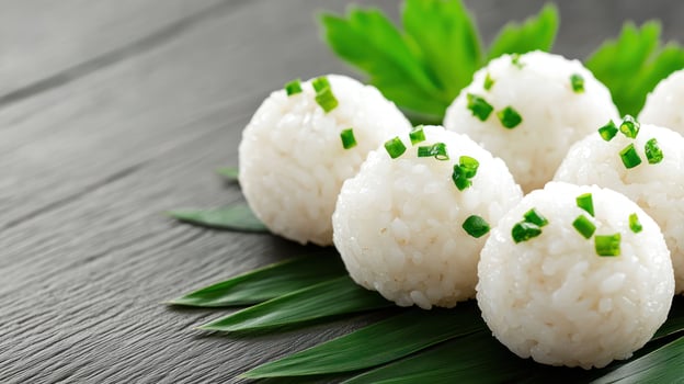 Rice balls with green garnish on leaves, resting on a gray wood surface. Food photography photo