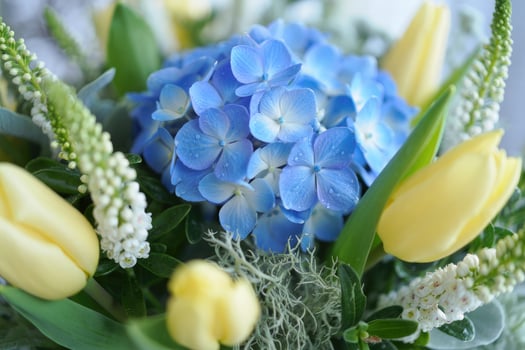 A stunning arrangement showcases blue hydrangeas and yellow tulips with fresh greenery. photo