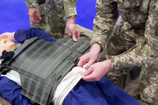 A man in military uniform conducts a master class on medical care on a mannequin photo