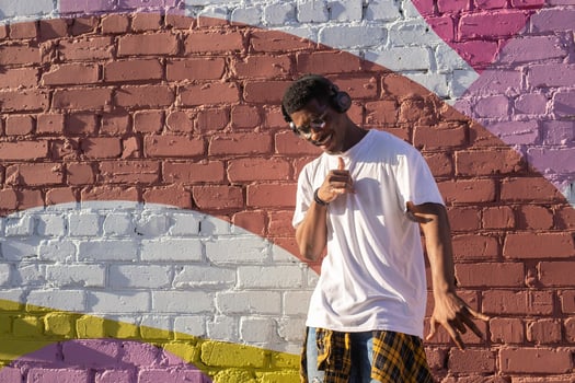 Young african american man dancing with headphones on colorful wall background. Copy space photo
