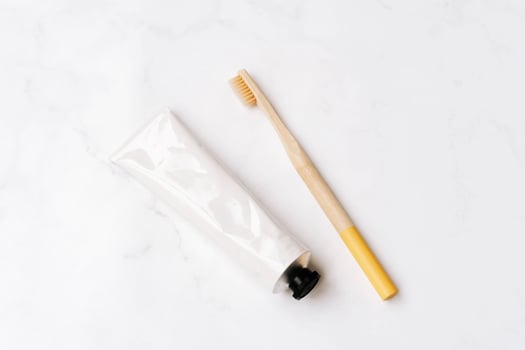 Top view of white metal tube without label and toothbrush on white background photo
