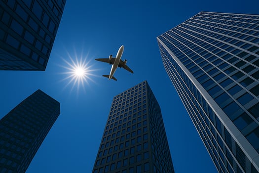 Airplane Flying Above Skyscrapers with Sunburst in Blue Sky photo