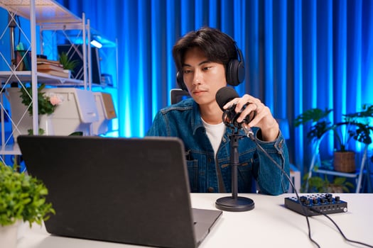 Young man working on podcast production with microphone and laptop in studio photo