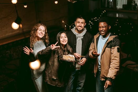 Friends celebrating together with cake in a cozy, dimly lit space during an evening gathering photo